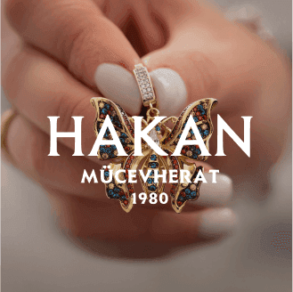 Close-up of a hand holding an exquisite butterfly-shaped jewelry piece with HAKAN MÜCEVHERAT 1980 text, demonstrating an elegant product ad template that leverages AI creative insights for optimized conversions on Instagram reels and social media ads.